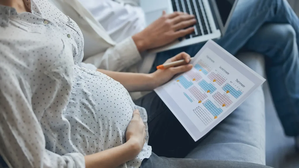 Pregnant woman reviewing documents on a laptop