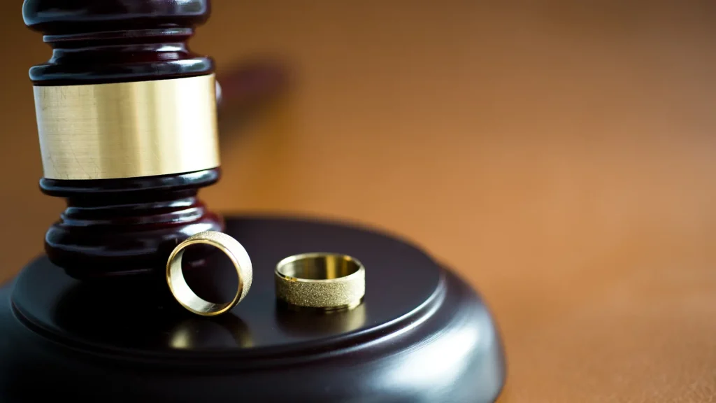 Two wedding rings next to a judge’s gavel on a block.